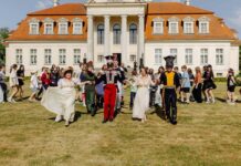 Szlak Pracy Organicznej Na zdjęciu widać pałac. Na tle pałacu ludzie w strojach z XIX wieku tańczą poloneza.